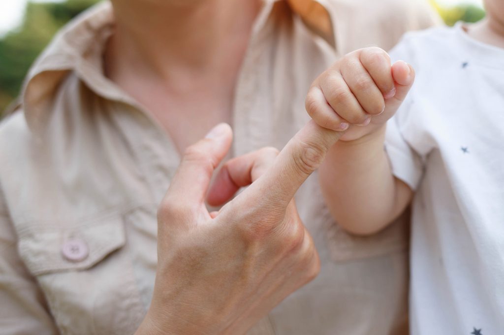 little boy holds mom's finger with a pen. close-up shot